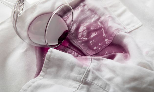 a glass full of wine is over to a white color coller shirt