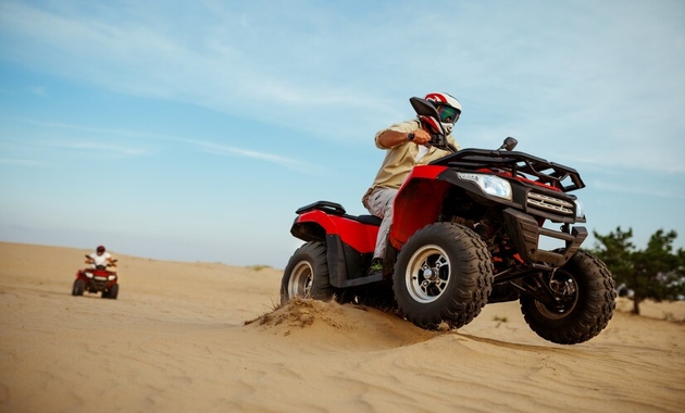 two boys are riding quad bike in desert