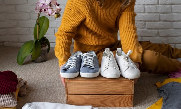 a woman is about to stuff newspaper in shoes for drying it quickly